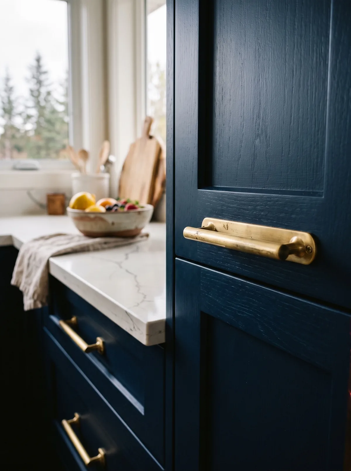 Brushed brass cabinet pulls on navy kitchen cabinetry